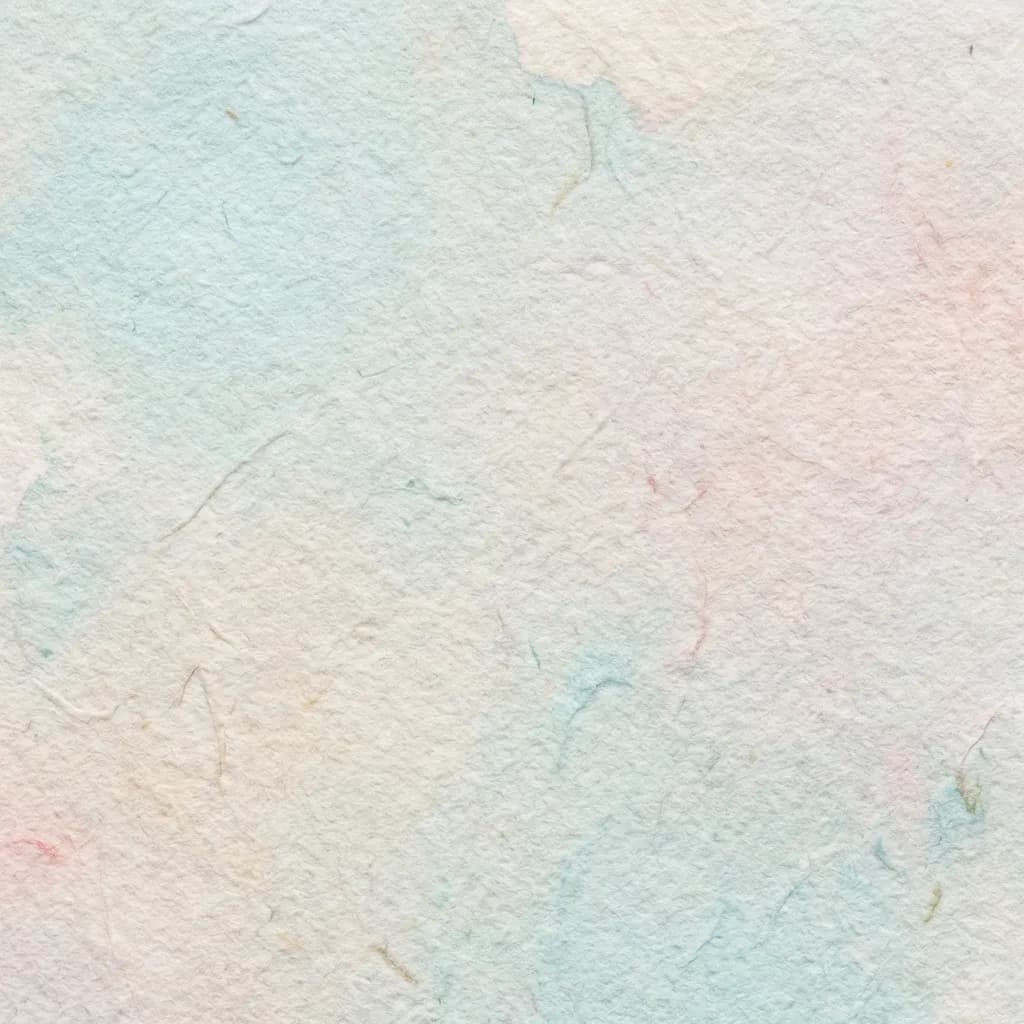 この画像は、繊細な手漉き紙のような質感のある背景を示しています。クリーム色の表面には、淡い水色とブラッシュピンクの柔らかなパステルカラーが優しく滲み、穏やかで芸術的な雰囲気を醸し出しています。紙の中に微細な繊維が見え、そのオーガニックで触覚的な質感を際立たせています。